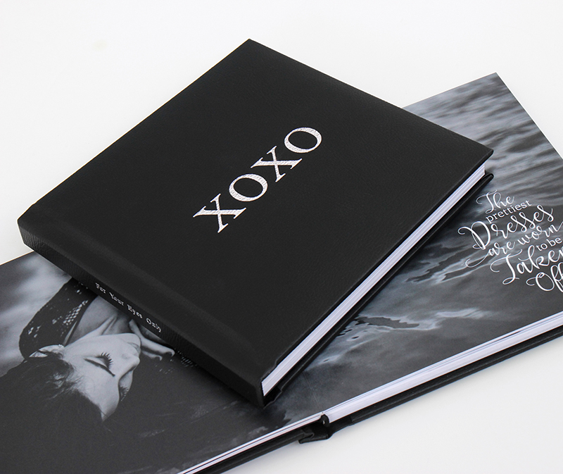 A boudoir book featuring a black leather cover and foil stamping.