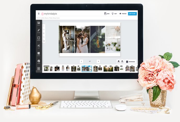 Desktop computer displaying an interface for editing a wedding photo album, with a desk setup including flowers and stationery.