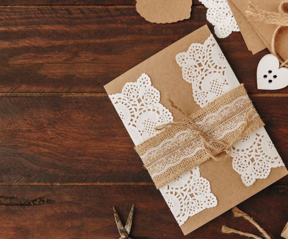 Handmade first anniversary wedding picture featuring lace, burlap ribbon, and a heart-shaped button on a dark wood surface. Envelopes are also visible.