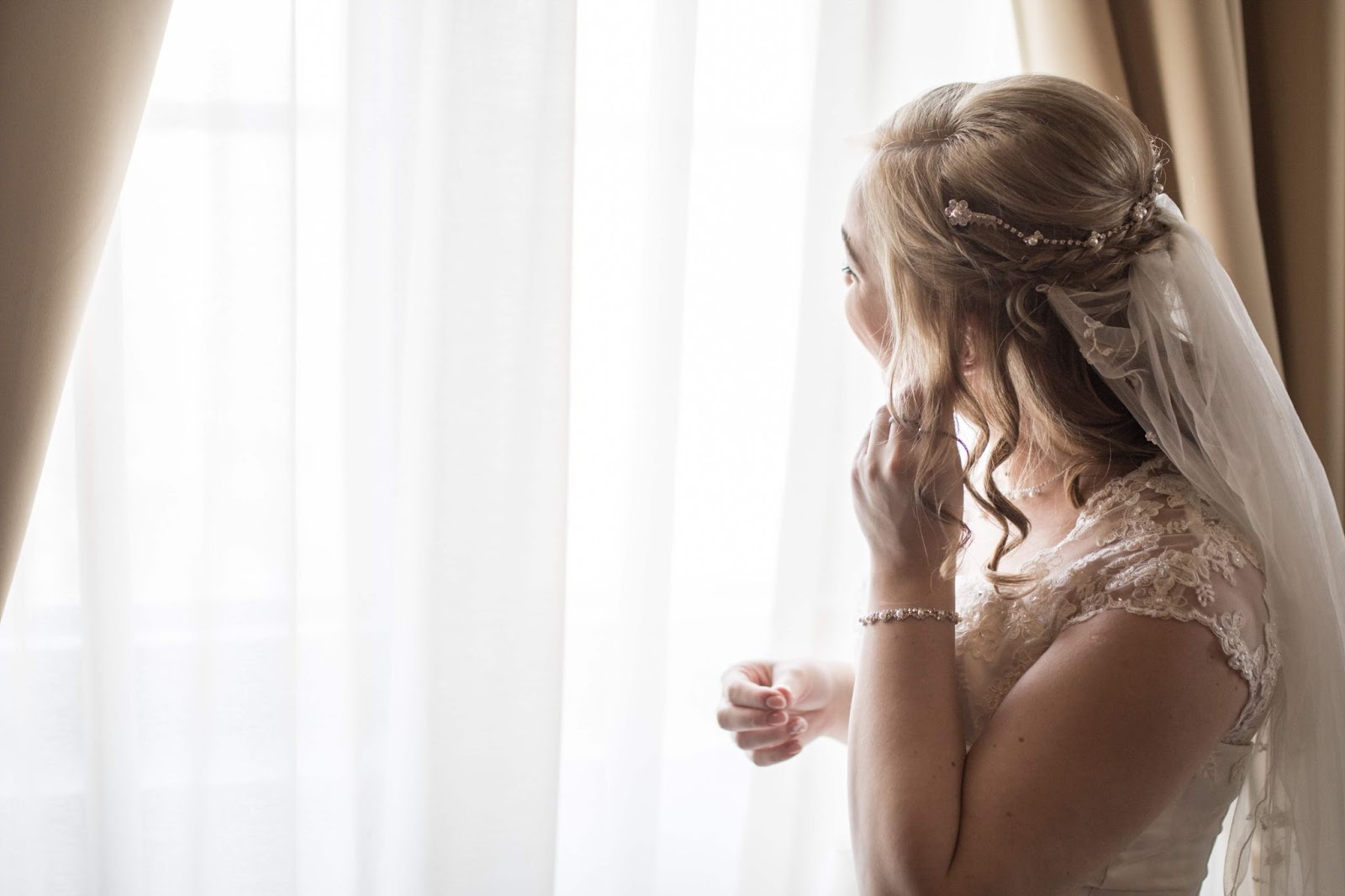 A beautiful bride getting ready and looking outside of the window. She's thinking about 2nd year anniversary gifts.