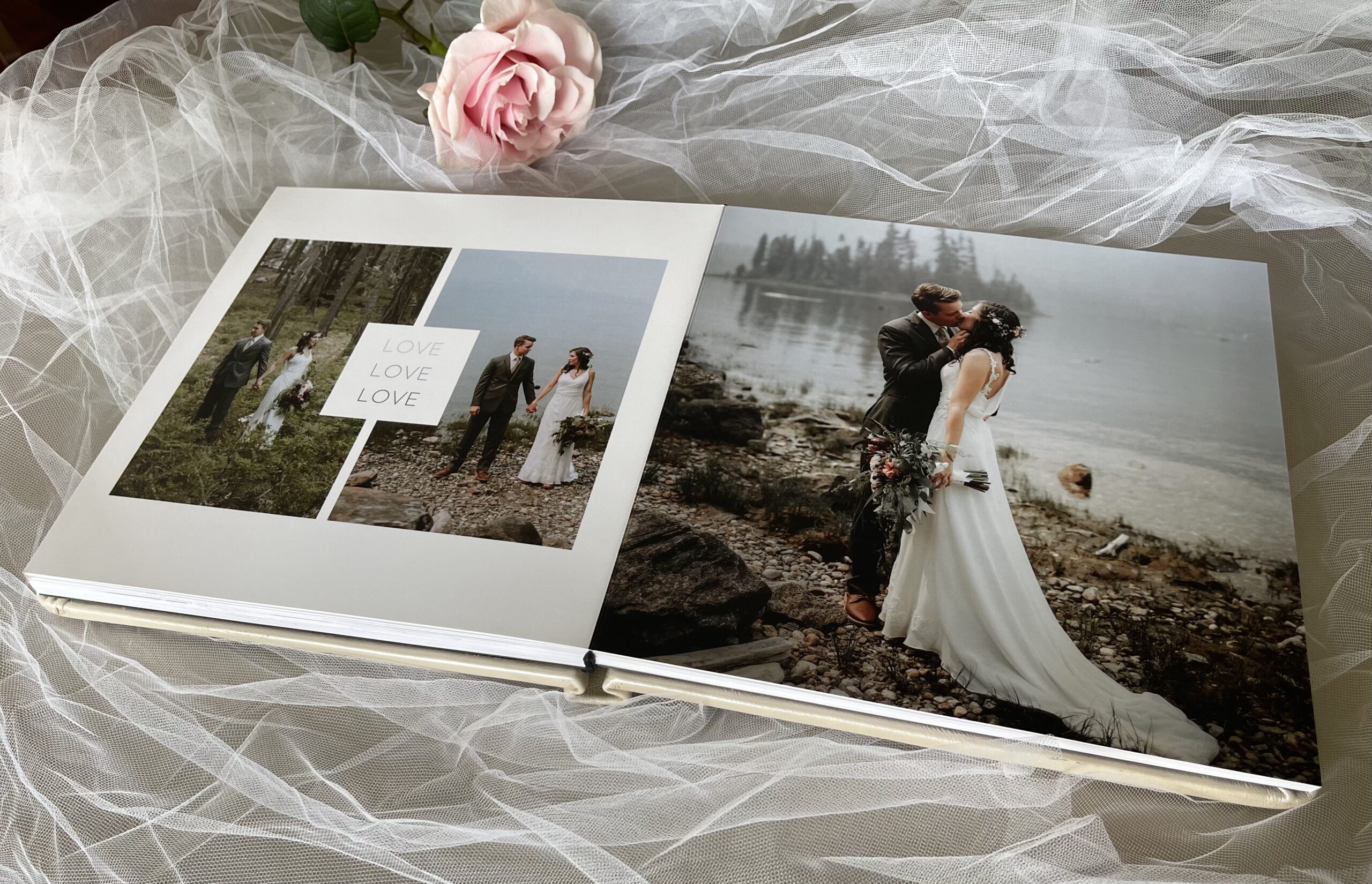 Wedding photo album open with bride and groom photos by a lake and forest, adorned with a pink rose and veil, capturing romantic moments.